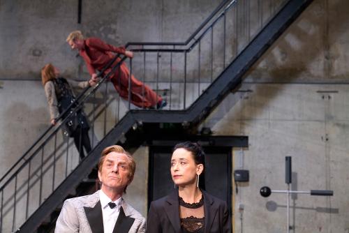 Bühnensituation: Im Vordergrund Magne Håvard Brekke und Sasha Rau, die ihn anschaut, er schaut geradeaus. Im Hintergrund Josefine Israel und Samuel Weiss auf einer schwarzen Metalltreppe. Josefine Israel hält sich mit beiden Händen am Geländer fest und lehnt sich leicht zurück, während sie nach oben zu Samuel Weiss schaut. Dieser hält sich ebenfalls mit beiden Händen fest und neigt sich mit geradem Körper zu ihr herunter.