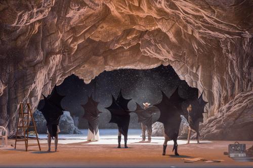 Das Ensemble steht verteilt auf der Bühne in einer Höhle. Alle umarmen sich selbst mit großen schwarzen Fledermausflügeln. Weiße Schnipsel fallen von der Decke.