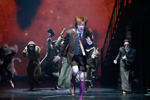 Jan-Peter Kampwirth ist im Vordergrund, hinter ihm mehrere Personen. Alle rennen in Richtung des Publikums und haben die Münder dabei geöffnet. 