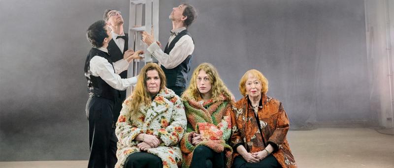 Ankündigungsfoto: Julia Wieninger, Alberta von Poelnitz und Ilse Ritter sitzen in farbig geblümten Mänteln nebeneinander und blicken in die Kamera. Hinter Ihnen stehen Ling Zhang, Stephan Krause und Peter Conradin Zumthor. Sie halten eine Leiter und blicken nach oben. Die Leiter ragt in eine Wolke am oberen Bildrand hinein.