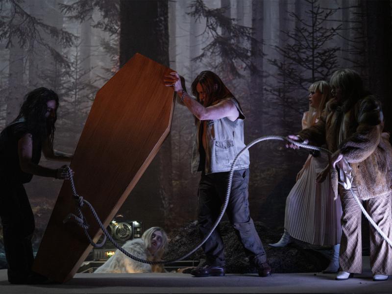 Martin Zamorano, Sébastien Jacobs, Sachiko Hara und Bettina Stucky bewegen gemeinsam einen Sargdeckel mithilfe eines Seils. Samuel Weiss befindet sich in einem Loch im Boden. Im Hintergrund das Bühnenbild, das einen düsteren Wald abbildet.