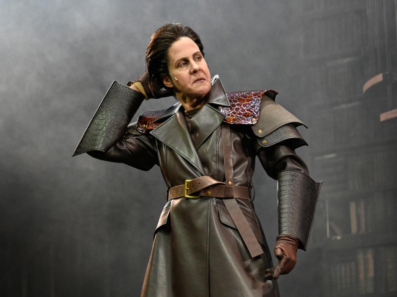 Ute Hannig steht im Nebel und greift sich mit der rechten Hand in die Haare. Sie trägt einen ledernen Mantel und blickt mit heruntergezogenen Mundwinkeln und von oben herab zur Seite.