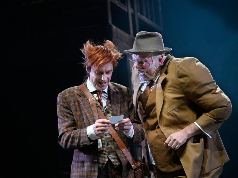 Jan-Peter Kampwirth hält einen kleinen Zettel in den Händen, auf den er hinunterblickt. Dicht neben ihm steht Yorck Dippe und schaut ebenfalls auf den Zettel. Beide haben den Mund leicht geöffnet.