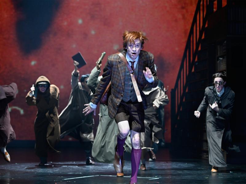 Jan-Peter Kampwirth ist im Vordergrund, hinter ihm mehrere Personen. Alle rennen in Richtung des Publikums und haben die Münder dabei geöffnet. 