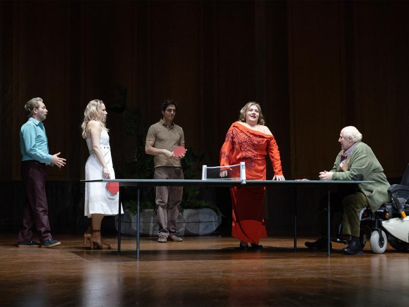 Josef Ostendorf, Josefine Israel, Pascal Houdus, Daniel Hoevels, Bettina Stucky und Samuel Weiss stehen verteilt an einer Tischtennisplatte. Josef Ostendorf, der in einem Rollstuhl sitzt, lehnt sich mit seinen Armen auf die Platte. Josefine Israel und Pascal Houdus halten einen Tischtennisschläger in der Hand. 