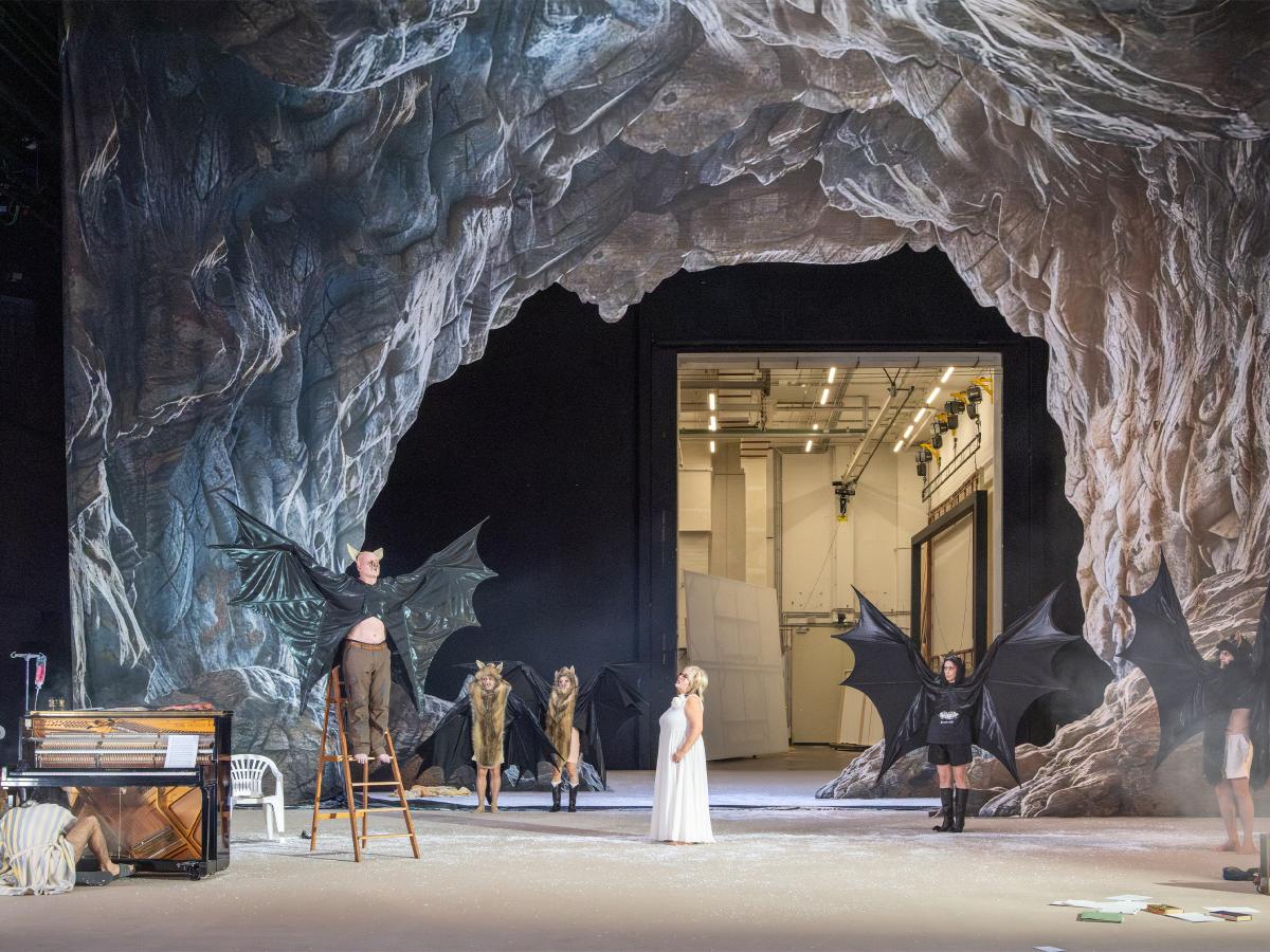 Das Ensemble steht verteilt auf der Bühne, Sébastien Jacobs auf einer Leiter. Alle tragen schwarze Fledermausflügel, die sie ausbreiten. Nur Bettina Stucky steht in einem weißen Kleid in der Mitte der Bühne. Im Hintergrund eine Felsenhöhle.