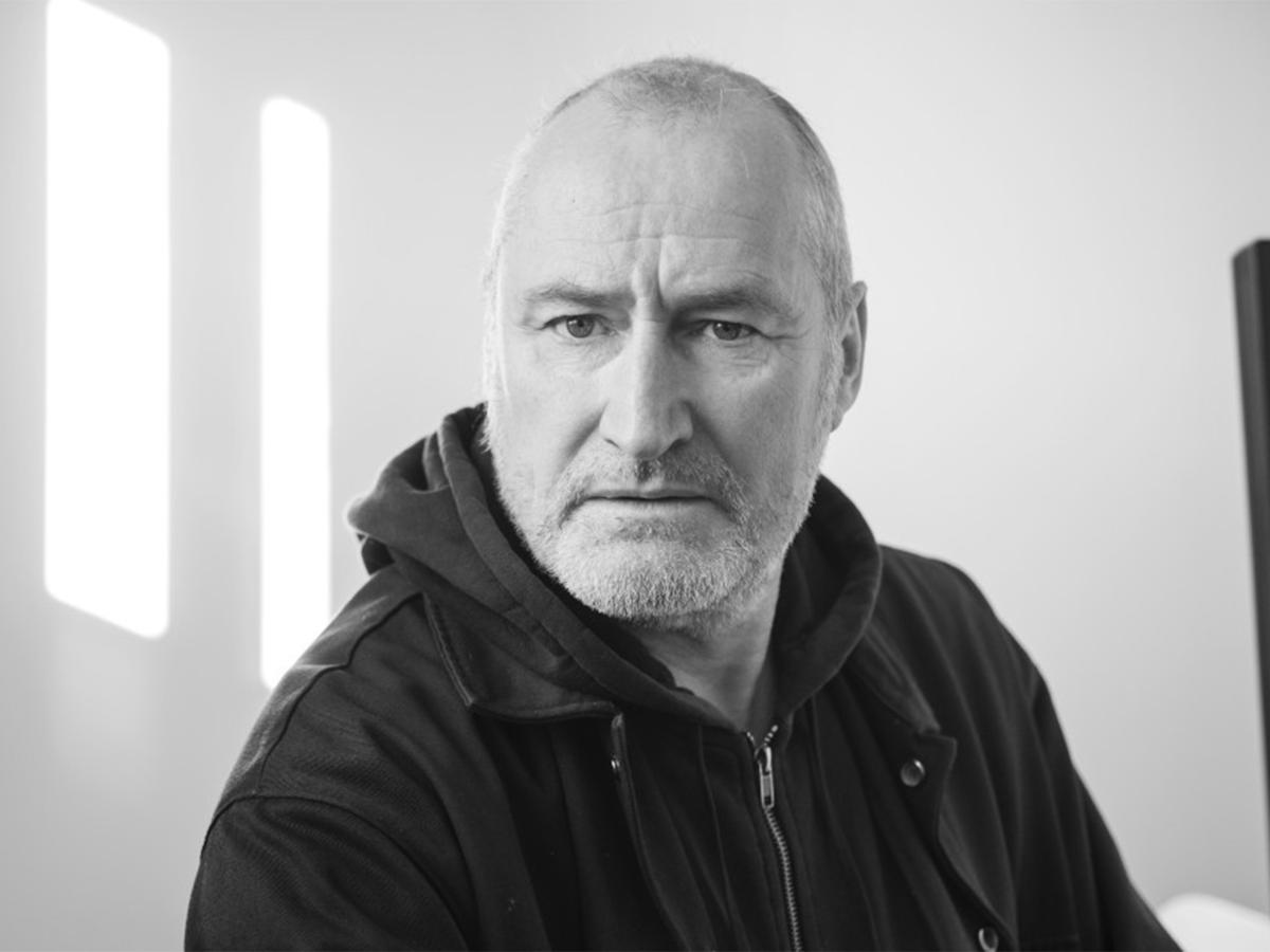 Schwarz-Weiß-Bild. Dramaturg Matthias Günther sitzt vor einem neutralen Hintergrund. Er trägt eine schwarze Jacke und schaut in die Kamera.